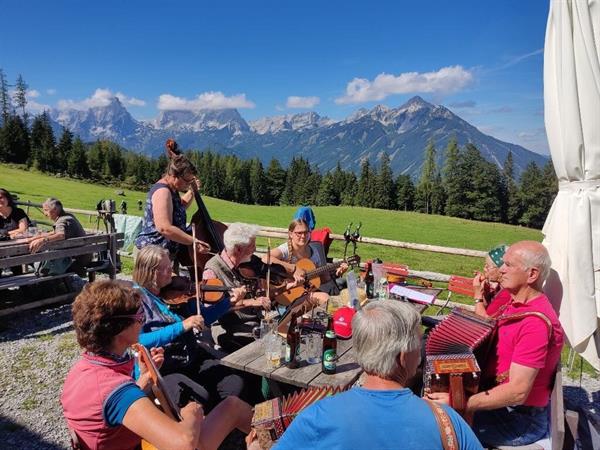 Eine Gruppe von Menschen, die um einen Picknicktisch sitzen, mit einer Person, die auf einem Berg im Hintergrund steht